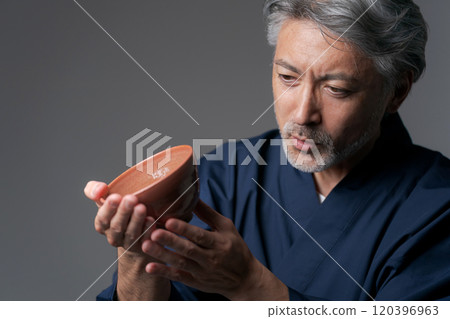 Image of a male potter holding a tea bowl 120396963