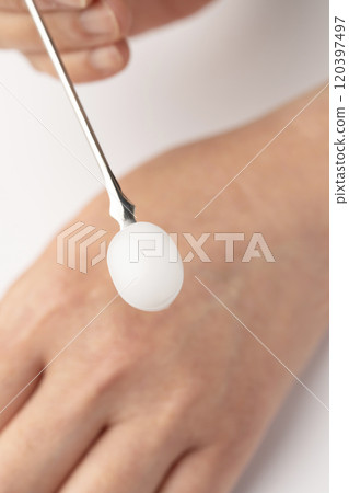 Take some moisturizing cream with a spatula and place it on the back of your hand. Take some moisturizing cream with a spatula and place it on the back of your hand. 120397497