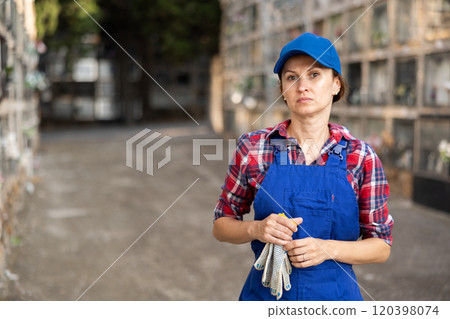 Female cemetery worker standing near columbarium wall 120398074