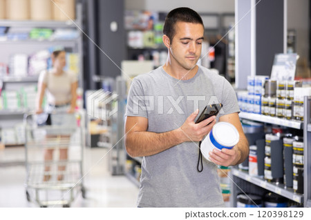 Man examines product in paint shop and scans QR code on label of enamel dye for painting walls. 120398129