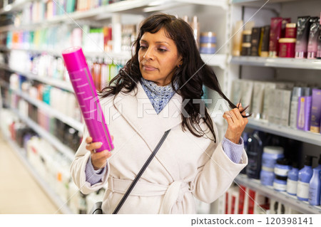 Woman choosing hair shampoo in cosmetics store 120398141