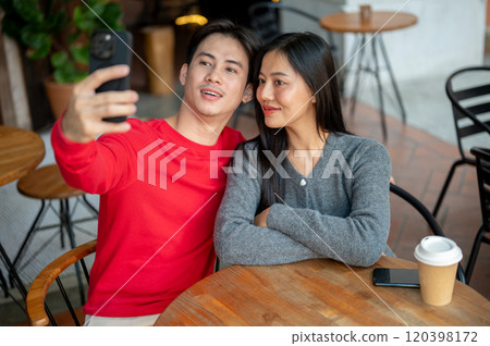 A sweet young Asian couple are taking selfies with a smartphone while enjoying a coffee date. A sweet young Asian couple are taking selfies with a smartphone while enjoying a coffee date. 120398172