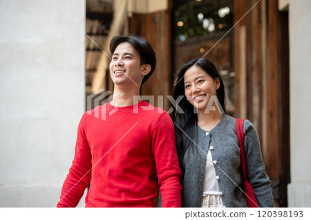 A lovely young Asian couple in cozy autumn clothes are enjoying a weekend shopping trip in the city. A lovely young Asian couple in cozy autumn clothes are enjoying a weekend shopping trip in the city. 120398193