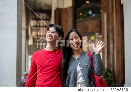 A lovely Asian couple enjoying a weekend date as they stroll through the city and shop together. 120398198