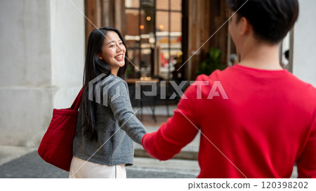 A charming, happy Asian girl enjoys a city stroll and shopping with her boyfriend, holding hands. A charming, happy Asian girl enjoys a city stroll and shopping with her boyfriend, holding hands. 120398202