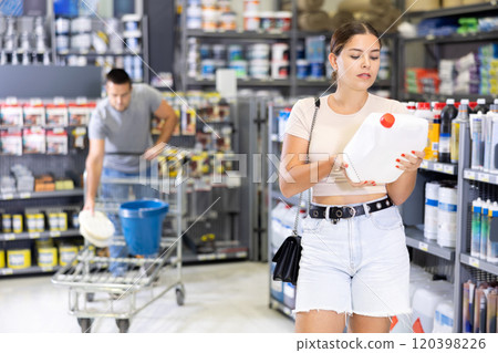 In store, woman hold plastic canister in hands and choice closely examines product In store, woman hold plastic canister in hands and choice closely examines product 120398226