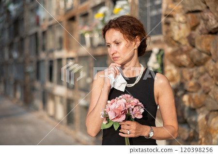Woman brought flowers to the cemetery and cries over the death of beloved relative Woman brought flowers to the cemetery and cries over the death of beloved relative 120398256