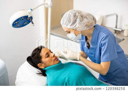 Cosmetologist making injections of botulotoxin into lips of Latin woman Cosmetologist making injections of botulotoxin into lips of Latin woman 120398258