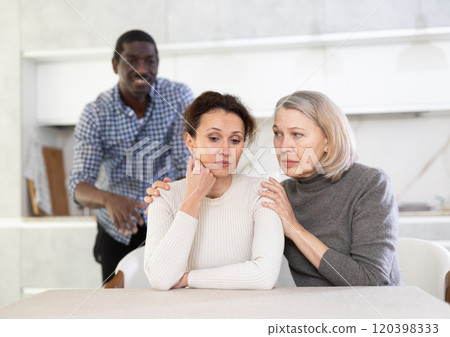 Old woman trying to calm angry middle-aged woman while man quarreling to her 120398333