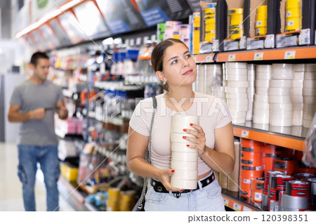 Woman buy sticky adhesive tape in construction store for carrying out internal finishing work 120398351
