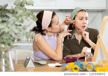 Two female friends examining faces in vanity mirror at home Two female friends examining faces in vanity mirror at home 120398642