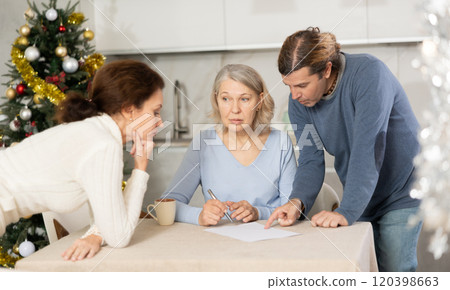 Man and woman help elderly mother make will and fill out document correctly On Christmas Eve Man and woman help elderly mother make will and fill out document correctly On Christmas Eve 120398663