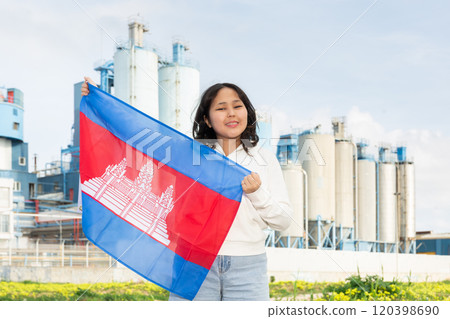 Happy asian girl with flag of cambodia standing in front of industrial scenery 120398690