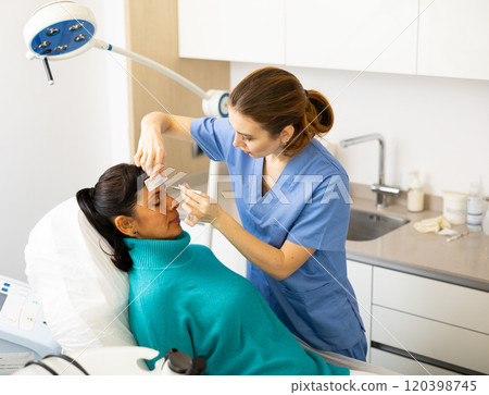 Female cosmetologist marking skin of hispanic with white pencil Female cosmetologist marking skin of hispanic with white pencil 120398745