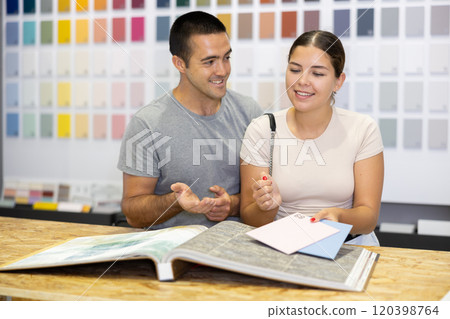 Smiling couple talking while browsing catalog with paint colors samples Smiling couple talking while browsing catalog with paint colors samples 120398764