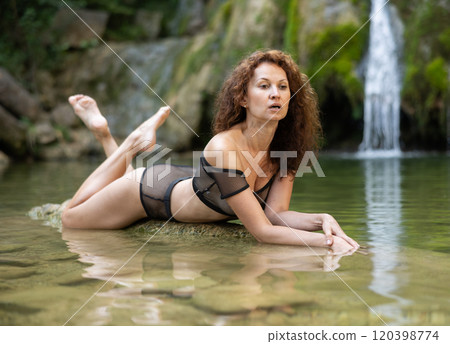 Sensual woman in transparent black lingerie lying by water Sensual woman in transparent black lingerie lying by water 120398774