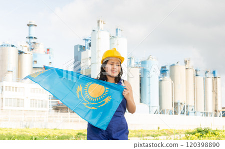 Happy asian girl in work clothes and hardhat with flag of kazakhstan standing in front of industrial scenery Happy asian girl in work clothes and hardhat with flag of kazakhstan standing in front of industrial scenery 120398890