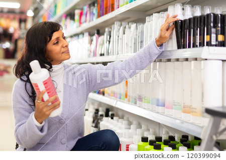 Latin american woman looking for haircare products at cosmetics shop Latin american woman looking for haircare products at cosmetics shop 120399094