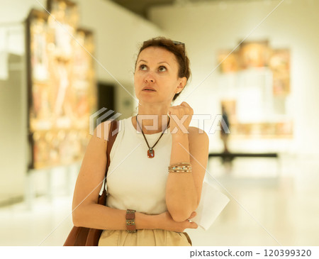 Woman viewing art gallery with brochure Woman viewing art gallery with brochure 120399320