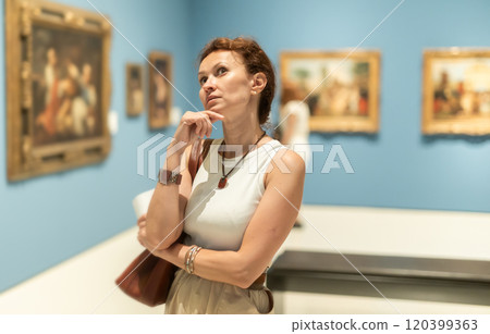 Closeup on attentive woman visiting museum and looking at exhibition of paintings 120399363