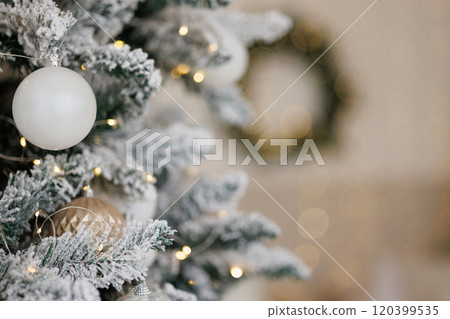 Close-up of a Christmas tree against a background of blurry garland lights. 120399535
