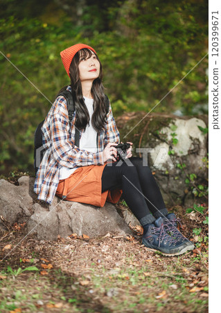 Woman climbing a mountain with a camera Woman climbing a mountain with a camera 120399671