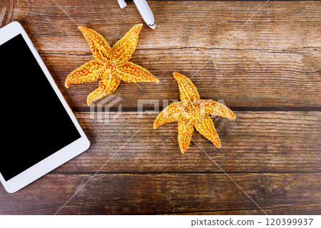 Starfish are arranged next to digital tablet PC on rustic wooden table with purchase online vacation ticket 120399937