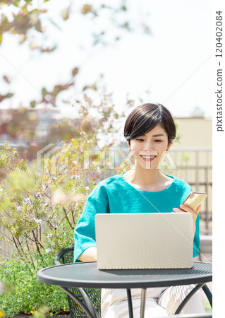 Woman using a computer on the roof terrace Woman using a computer on the roof terrace 120402084