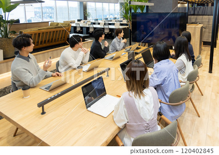 Men and women having a meeting using a monitor Men and women having a meeting using a monitor 120402845