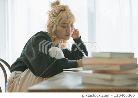 一位年輕的金髮女郎正在為她的夢想而學習 120403360