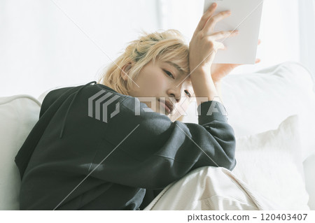 Blonde woman sitting on the sofa and reading a book 120403407