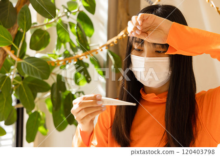 一位身體不適的年輕女性用溫度計檢查體溫 120403798