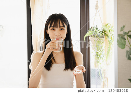 young woman taking supplements 120403918