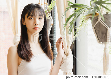 A young woman standing at the window A young woman standing at the window 120404013