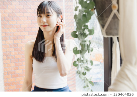 Young woman listening to music by the window Young woman listening to music by the window 120404026