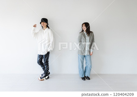 A stylish couple leaning against a white wall 120404209