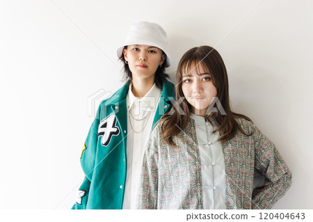 A stylish couple leaning against a white wall A stylish couple leaning against a white wall 120404643