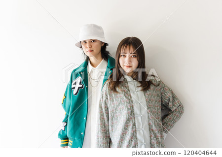 A stylish couple leaning against a white wall 120404644