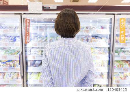 Woman looking at frozen foods at the supermarket, back view, shopping scene 120405425