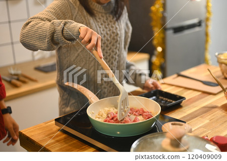 Young woman wearing a gray knit sweater preparing meal in a cozy kitchen Young woman wearing a gray knit sweater preparing meal in a cozy kitchen 120409009