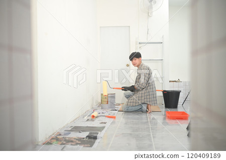 Young asian man working on a home improvement project, painting a wall in the empty room 120409189