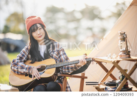 Woman playing guitar at campsite Woman playing guitar at campsite 120409393