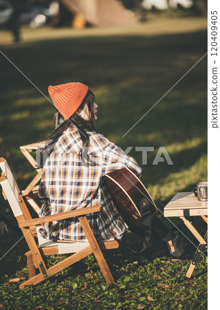 Woman playing guitar at campsite 120409405