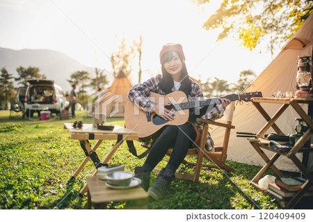 Woman playing guitar at campsite Woman playing guitar at campsite 120409409