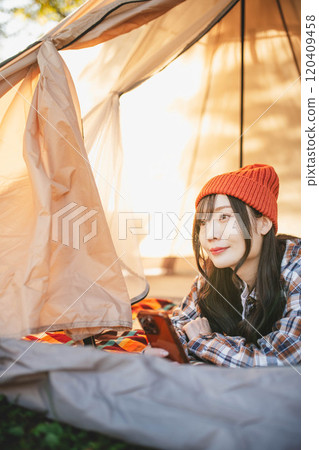 一位女士在露營時睡在帳篷裡玩智慧型手機 一位女士在露營時睡在帳篷裡玩智慧型手機 120409458