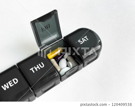 Weekly pill organizer with various medication on light background 120409538