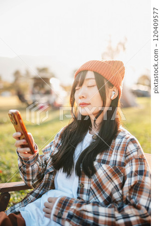 坐在露營地聽音樂的女人 120409577