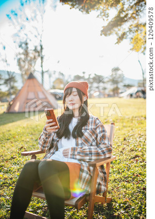 坐在露營地聽音樂的女人 120409578