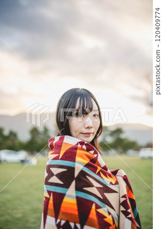 A woman wrapped in a blanket gazing into the distance A woman wrapped in a blanket gazing into the distance 120409774