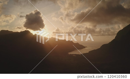 Golden sunlight beams streams through clouds, casting a warm glow over mountain silhouette valley and tranquil ocean lagoon. Moorea, French Polynesia, creating a breathtaking tropical sunset panorama Golden sunlight beams streams through clouds, casting a warm glow over mountain silhouette valley and tranquil ocean lagoon. Moorea, French Polynesia, creating a breathtaking tropical sunset panorama 120410360